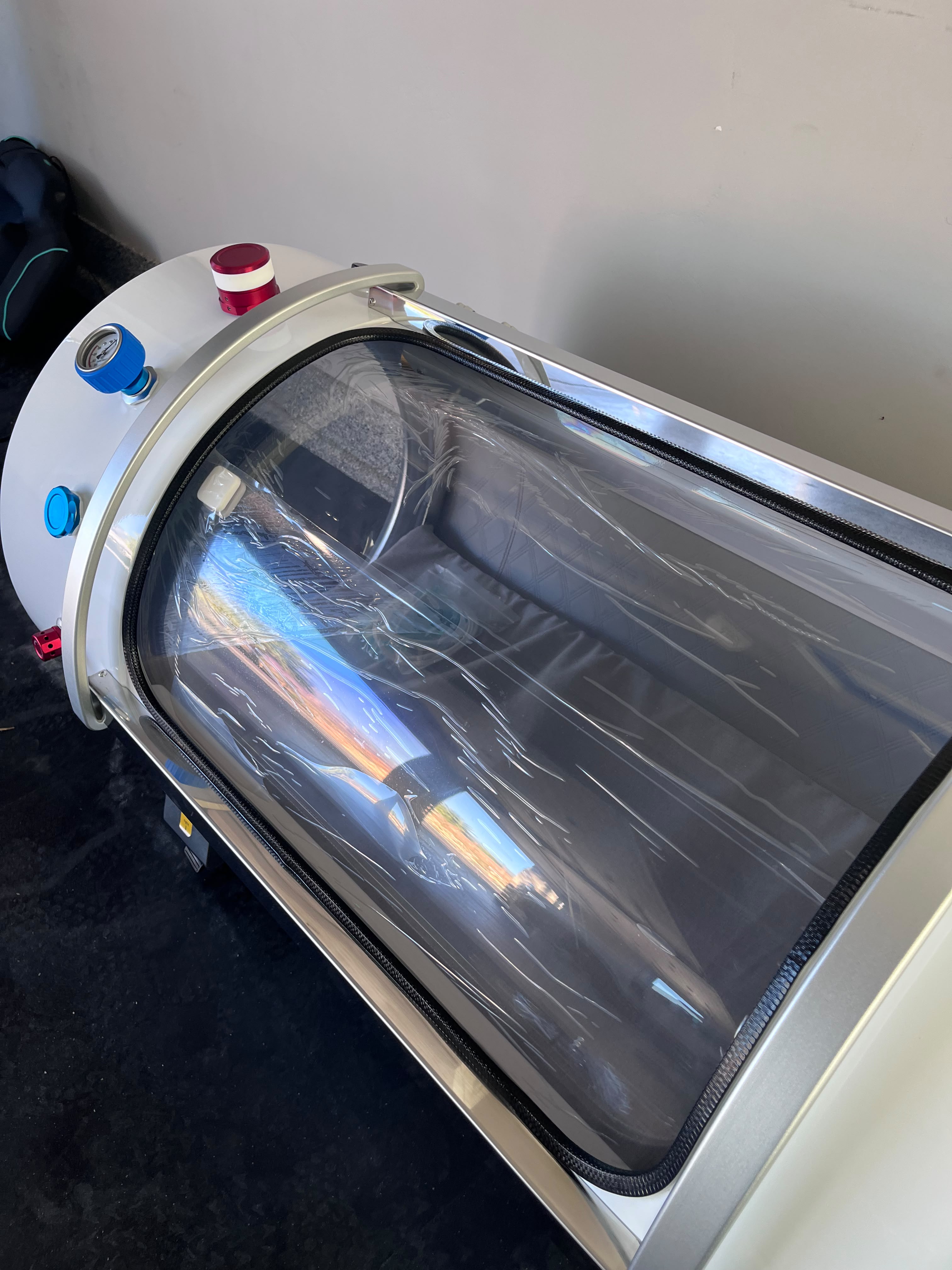 A hardshell chamber's curved viewing window and exterior controls in a private wellness room